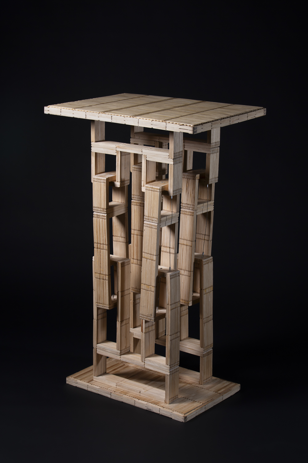 Proof — a tensegrity table built from craft sticks, photographed on a black background