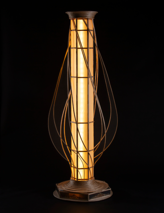 Vessel sculpture lit from within, standing in a living room